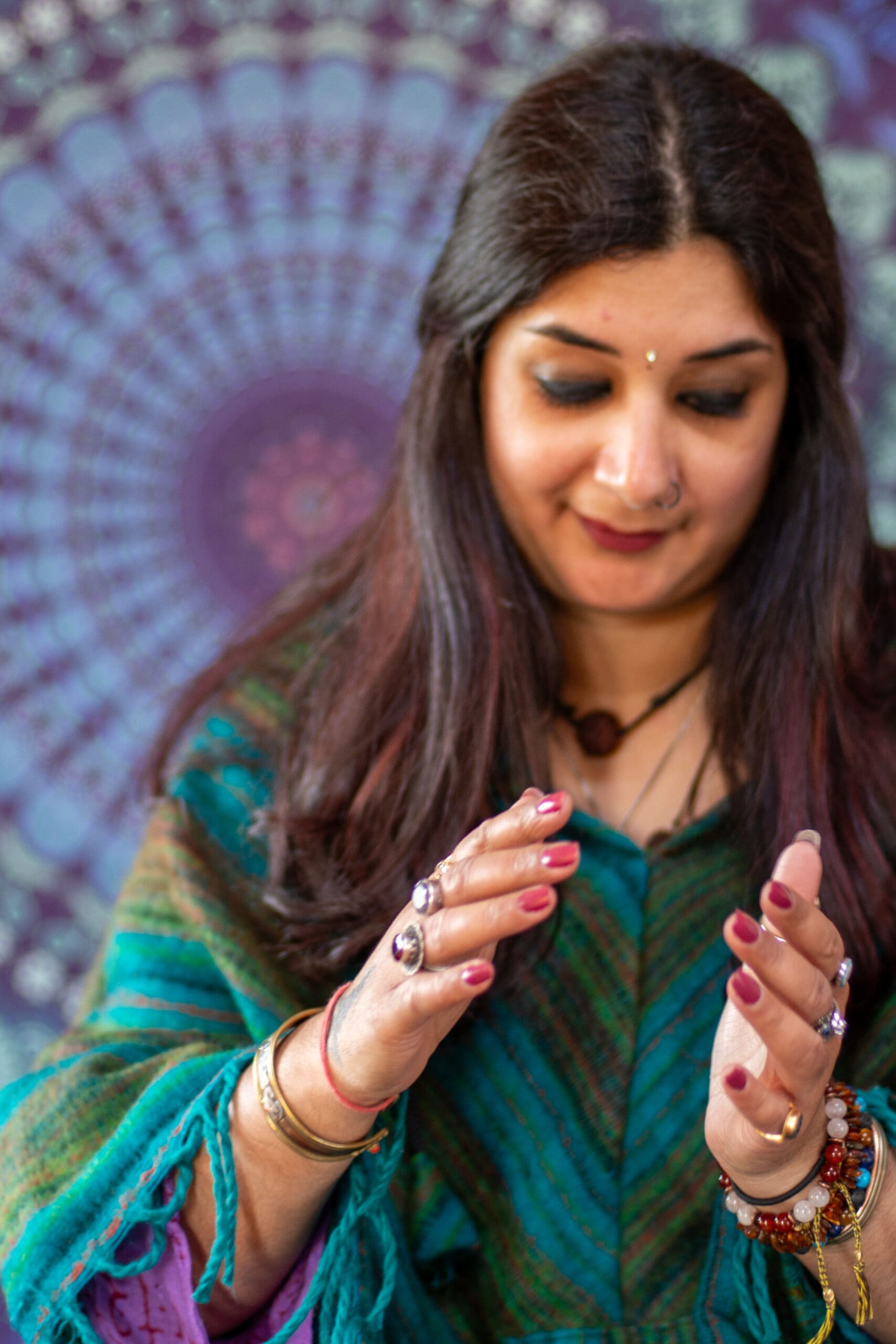 Sunny holds an energy ball in her hands as she sits in front of a mandala scarf.